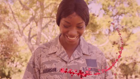 animation of hearts over happy african american female soldier