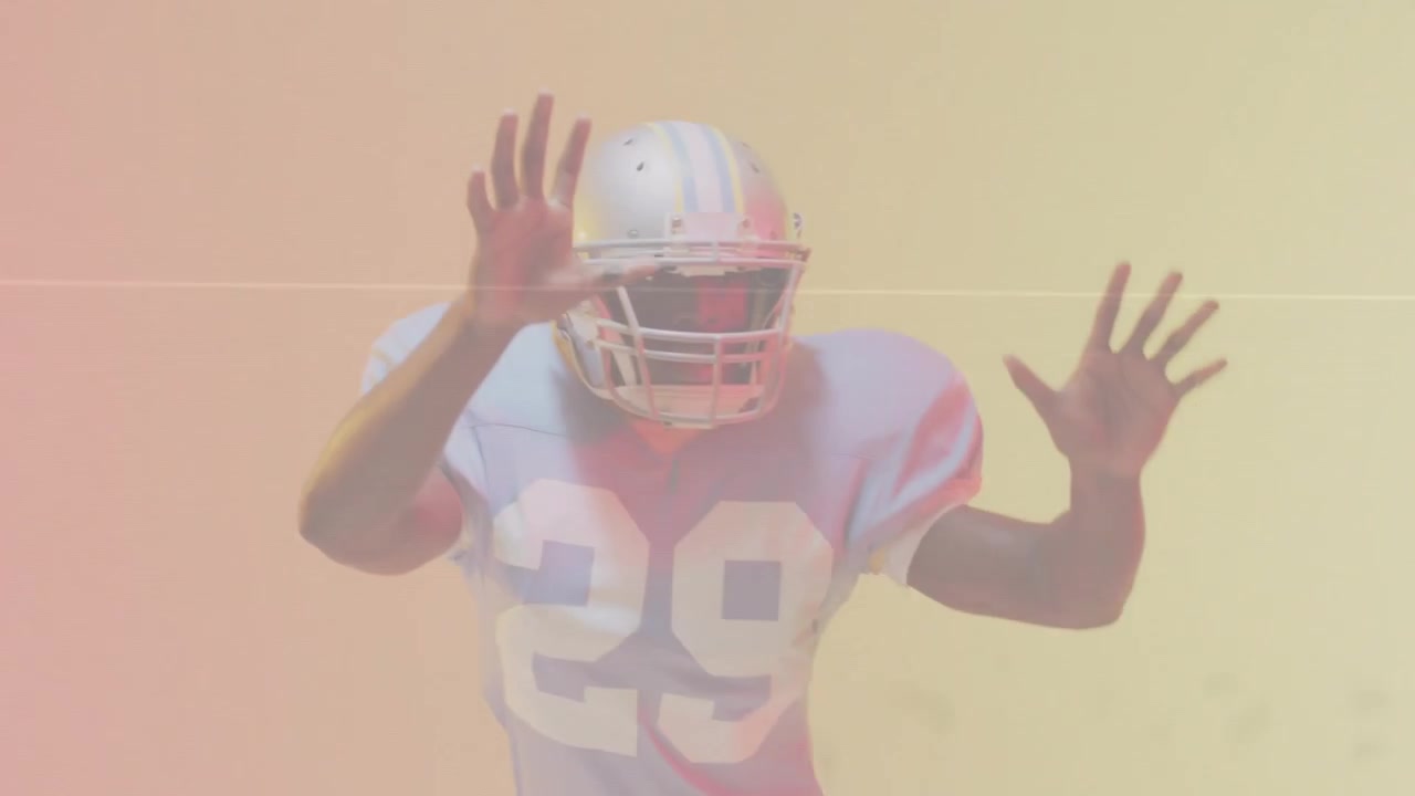 Giocatore di football americano che reagisce a un glitch, alzandosi, ruotando, alzando le braccia, mostrando casco e maglia numero 29 per una pubblicità.