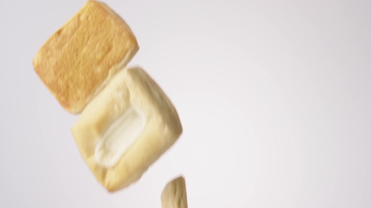 Golden flaky cream-filled danishes streaming down on white tabletop in mesmerizing slow motion. office catering content, sunday brunch reels, mothers day breakfast posts.