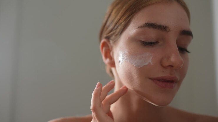 Donna che applica crema per il viso