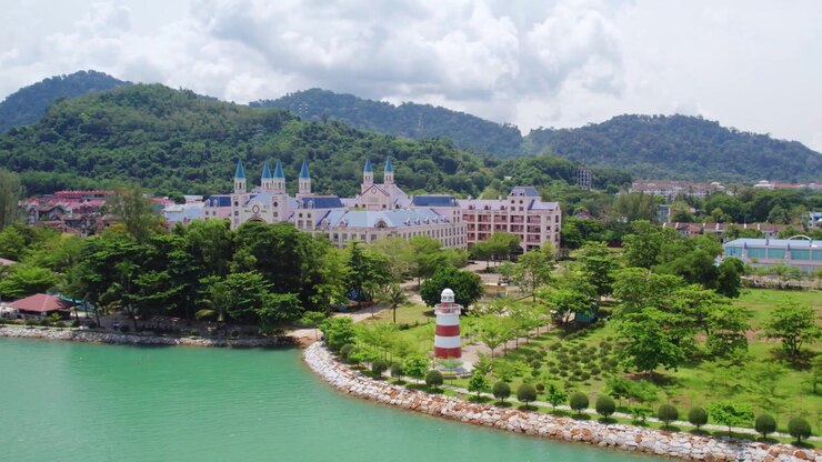Cảnh quay drone xoay tròn mượt mà giới thiệu ngọn hải đăng quyến rũ bên bờ biển dọc theo bờ biển nhiệt đới của Langkawi với làn nước xanh ngọc bích, những ngọn đồi rừng nhiệt đới tươi tốt và khung cảnh ven biển đẹp như tranh