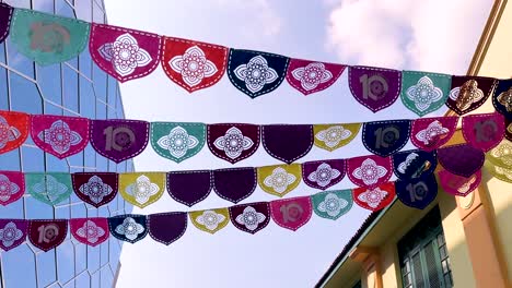 rows of vibrant decorative flags flutter overhead between modern glass buildings and traditional architecture, captured with smooth upward camera movement in natural daylight