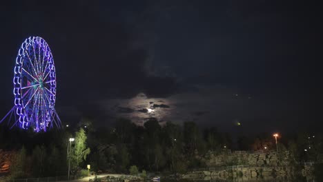 rueda de la ferris de la noche bajo una luna nublada