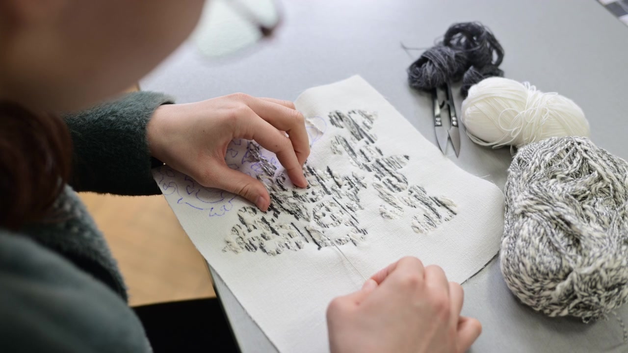 Close up of hands working with textile samples or fabric swatches on a design table, showing attention to detail in material selection and fabric composition