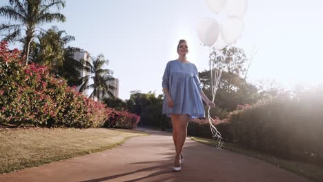 feliz hermosa mujer latina caminando en el parque. joven chica rubia disfruta del día en cámara lenta. caminando por el parque con globos. 4k. cinematográfico premium
