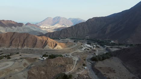 Montañas-De-Los-Emiratos-árabes-Unidos:-Vista-Superior-Del-Pueblo-Y-Las-Montañas-De-Khorfakkan,-Una-Ciudad-Tradicional-Del-Norte-Entre-Las-Colinas