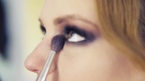 Vista-De-Cerca-Del-Maquillador-Aplicando-Sombra-De-Ojos-En-El-Párpado-Con-Una-Brocha-De-Maquillaje.-Maquillaje-Profesional.-Tiro-En-Cámara-Lenta