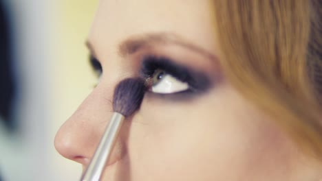 vista de cerca del artista de maquillaje aplicando sombra de ojos en el párpado usando un pincel de maquillaje. maquillaje profesional. toma en cámara lenta
