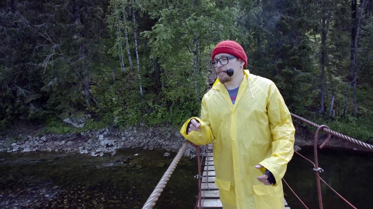hombre caminando en un puente de madera a través del bosque y el río