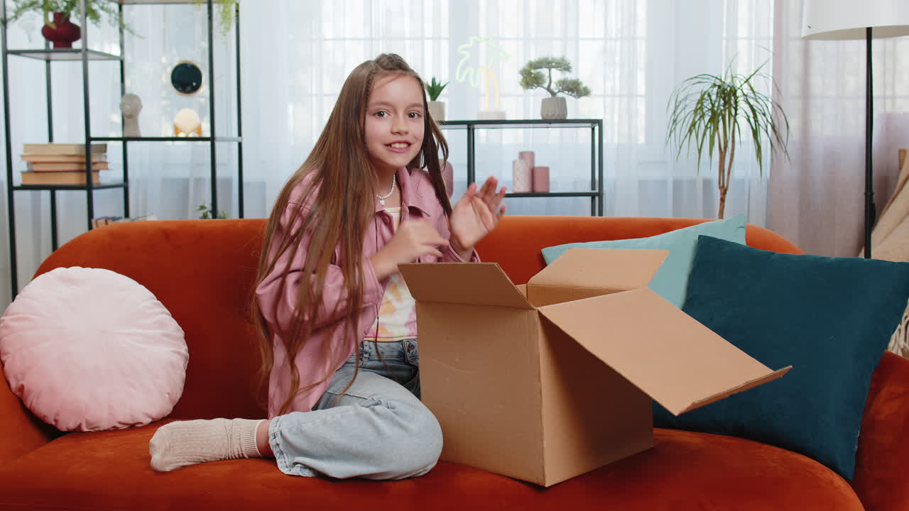 Happy amazed child kid girl unpacking delivery parcel opening cardboard box receiving purchase gift