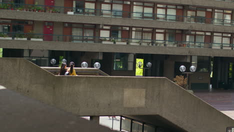 Two Young Female Friends Walking Through The Barbican Centre In City Of London Together