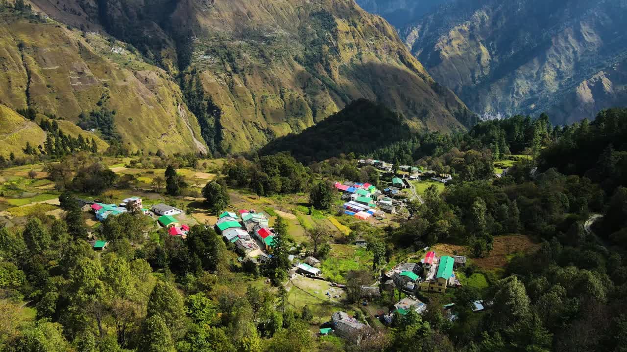 Aerial drone shot featuring a quaint village nestled among green hills with mist rolling through.