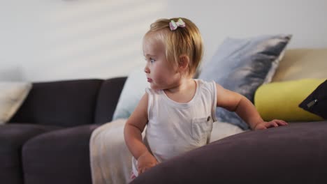 Cute-caucasian-baby-standing-while-holding-the-couch-at-home