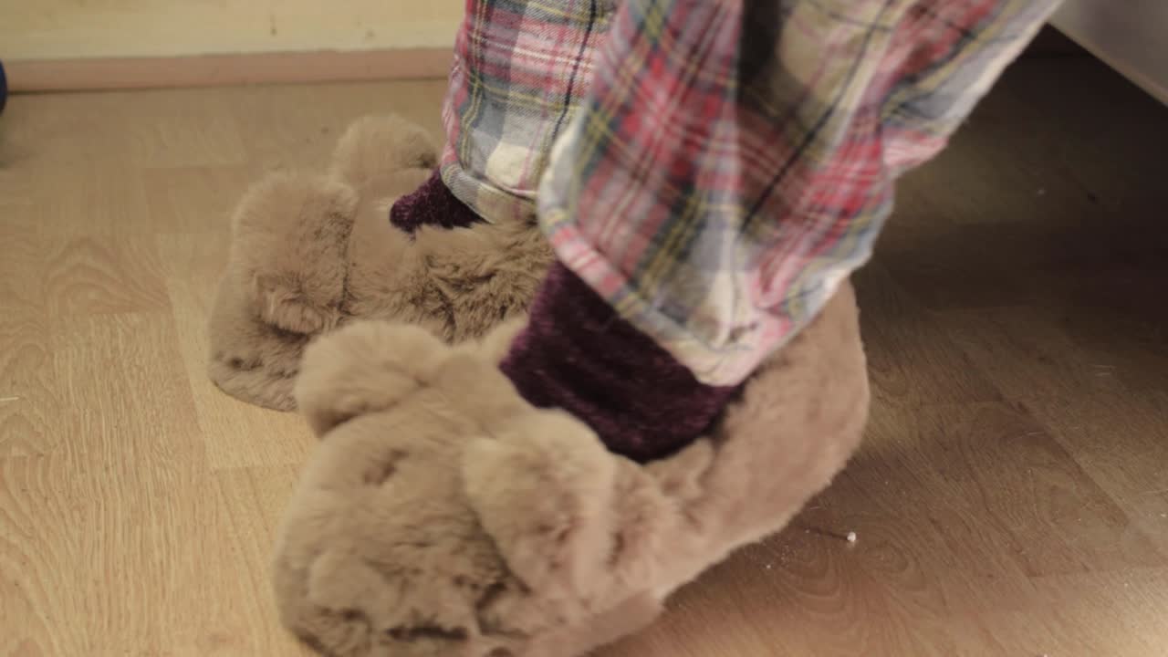 Woman putting on fluffy slippers and walks after waking up