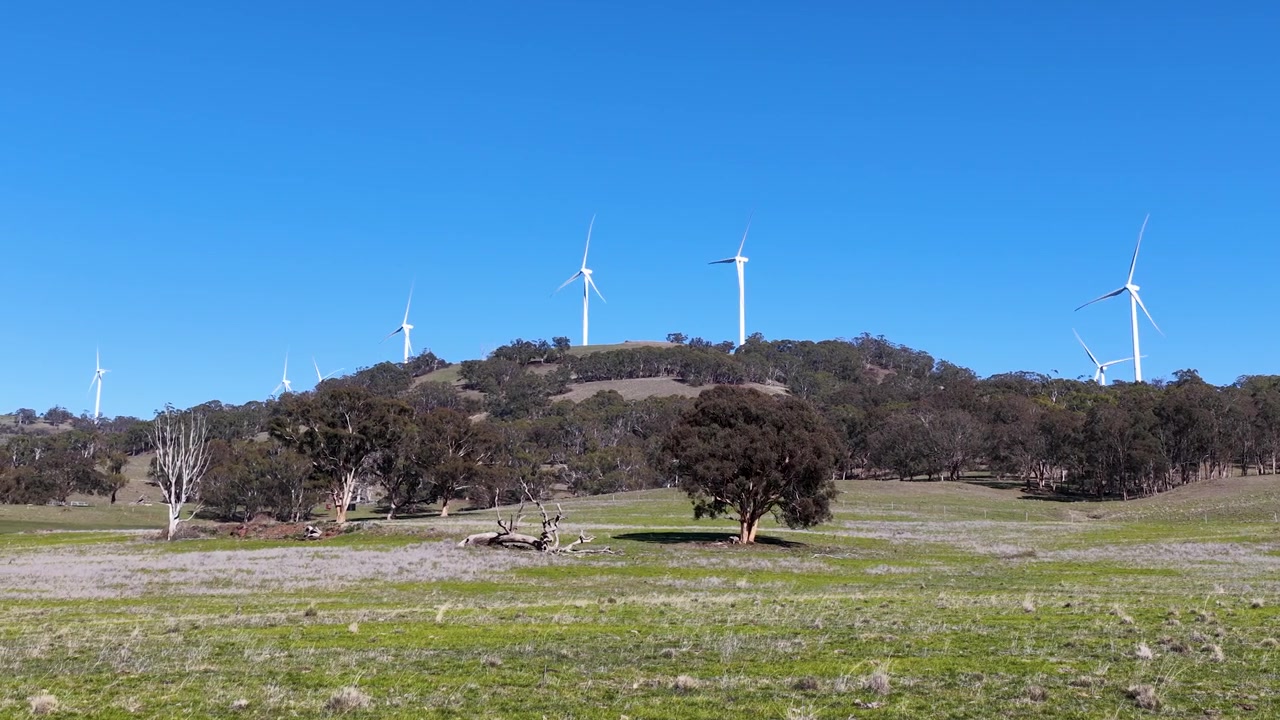 Veduta ampia di turbine eoliche per energia rinnovabile che girano su un paesaggio rurale australiano a Matheson