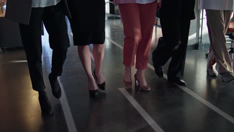 Close-up-shot-of-a-group-of-confident-girls-walking-along-a-corridor-in-an-office-on-a-gray-floor-confidently-stepping-forward.-A-group-of-businesswomen-walk-confidently-on-the-gray-floor-in-the-office