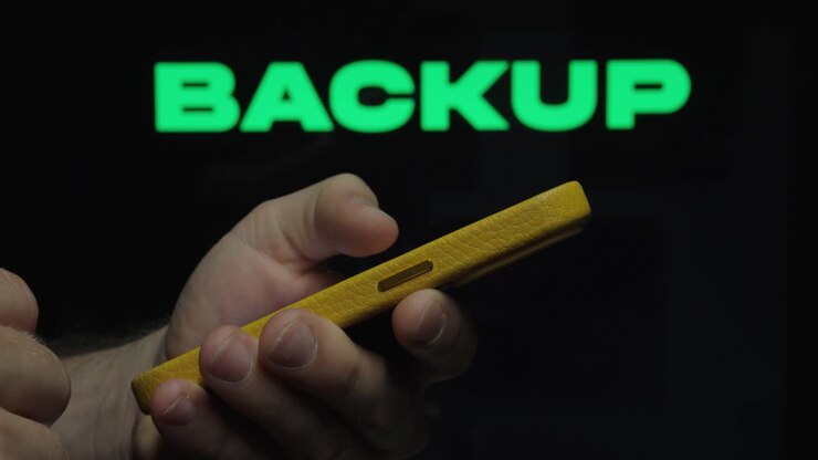 Close-up of a hand using a smartphone with “Backup” text, representing data protection, storage, and digital security