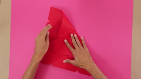 marking fold marks on red hard paper for origami on pink paper