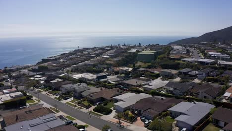 Reverse-pullback-aerial-shot-of-a-Malibu-Bluffs-neighborhood-along-the-Pacific-Ocean