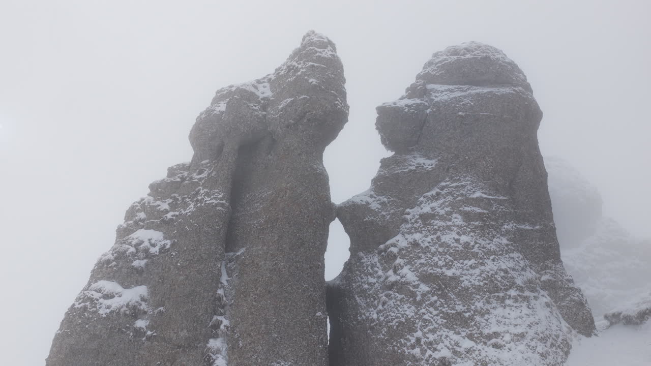 Aerial drone view of Babele la Sfat (Old Ladies's Council) rock formation covered in snow in winter season. Romania, Carpathian Mountains