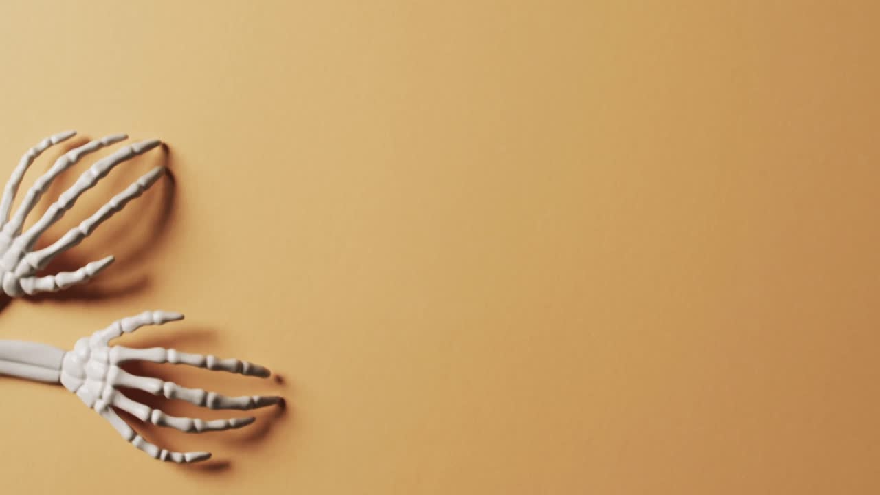 video de las manos del esqueleto de halloween con espacio de copia en fondo naranja