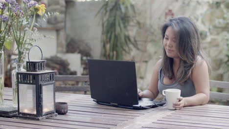 medium shot of pretty woman sitting at table in cafe with laptop