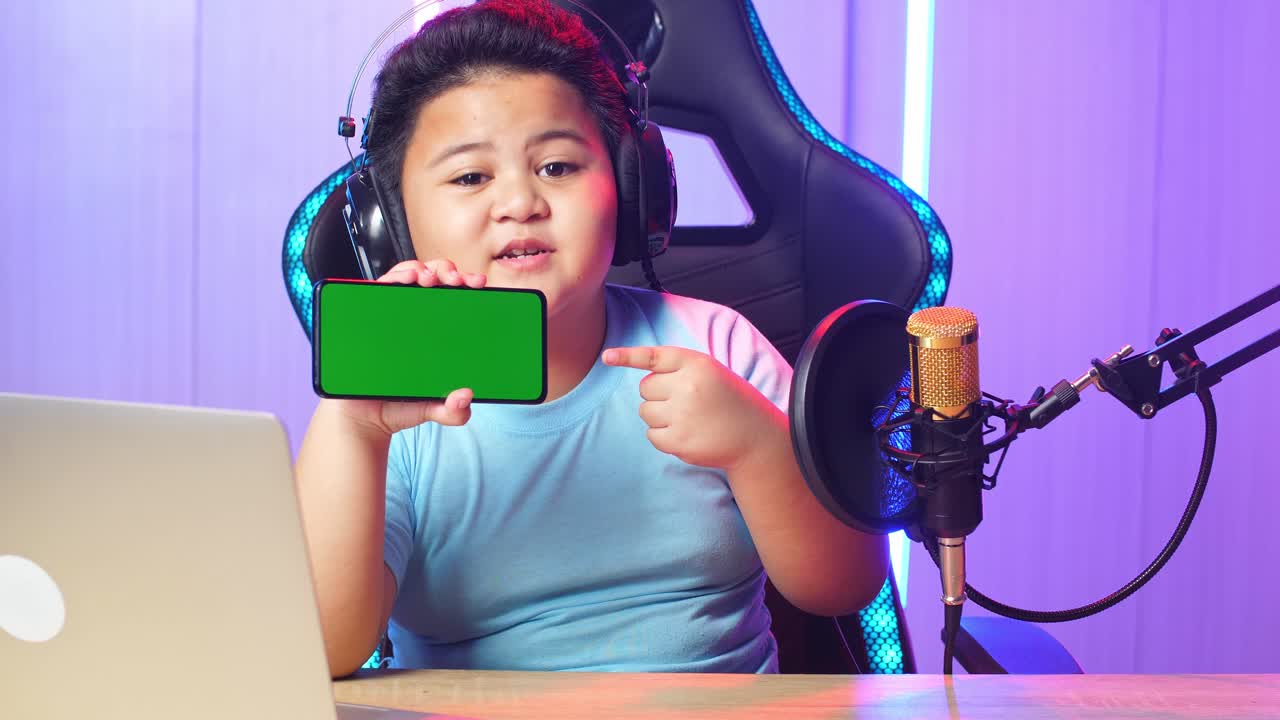 Asian Little Boy Holding Mobile Phone With Mock Up Green Screen And Talking While Live Stream