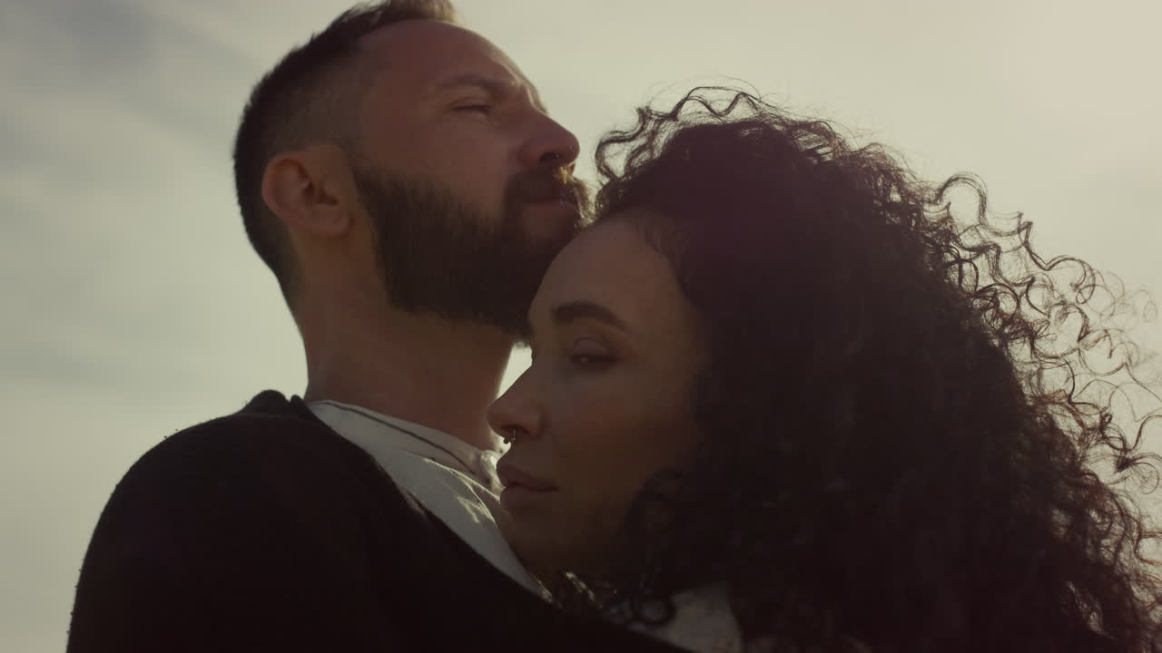 Amantes multiétnicos abrazándose al aire libre al atardecer. Pareja atractiva que se ama.