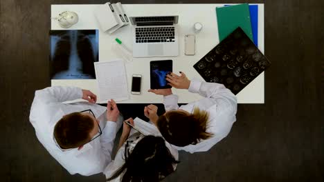 equipo médico discutiendo el diagnóstico de las imágenes de rayos x utilizando una tableta especial