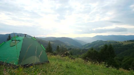 tent stand in beautiful green mountains aerial view single one tent on hilltop with green caucasus mountains panorama green camping tent on top of mountain with amazing sunrise on background time spending on fresh air traveling concept