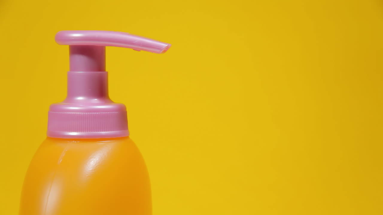 Un flacone dosatore di sapone in plastica arancione su una superficie rotante