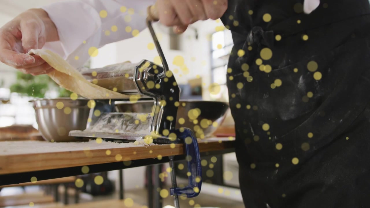 Chef che posiziona l'impasto, bloccando il rullo e girando la manovella per guidare la sfoglia di pasta sottile, con punti gialli sulle mani.