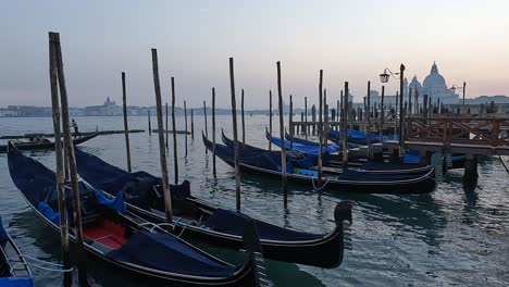 Docked-gondolas-at-sunset-with-Santa-Maria-Della-Salute-church-in-background,-Venice-in-Italy