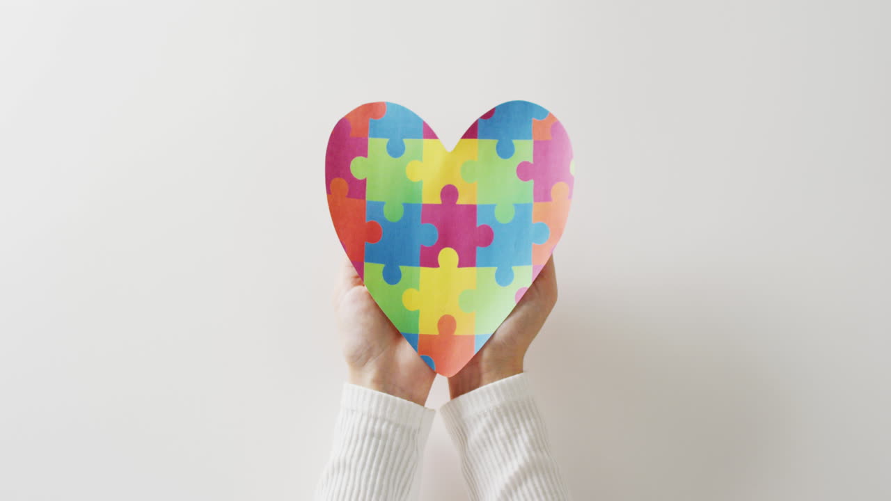 Video di mani che tengono un cuore a puzzle su sfondo bianco con spazio per il testo