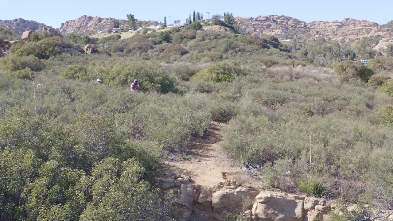 MTB mountain bikers riding off cliff downhill fast, jumps