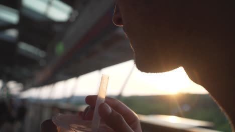 A-young-man-is-drinking-bubble-tea,-while-he-sits-on-a-sunny-terrace