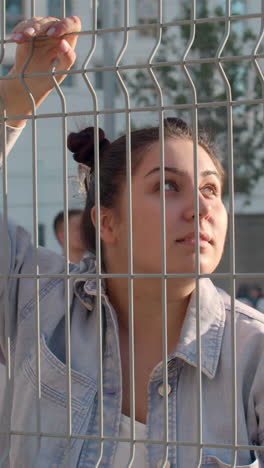 woman looking up through a metal fence