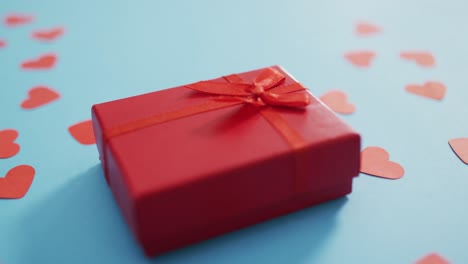 multiple red paper hearts and red present at valentine's day on blue background