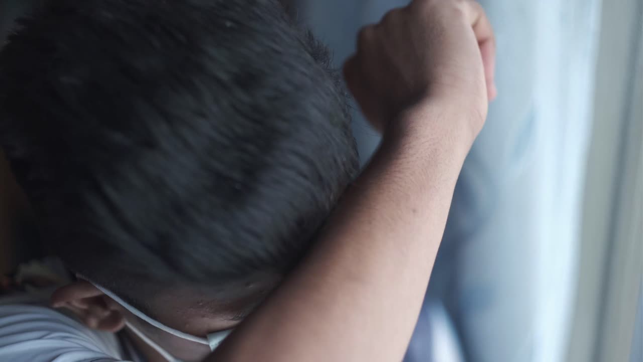 마스크를 착용 한 젊은이가 창밖을 바라보고 있습니다.