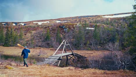 man walking and carrying oars in åfjord, norway - wide shot