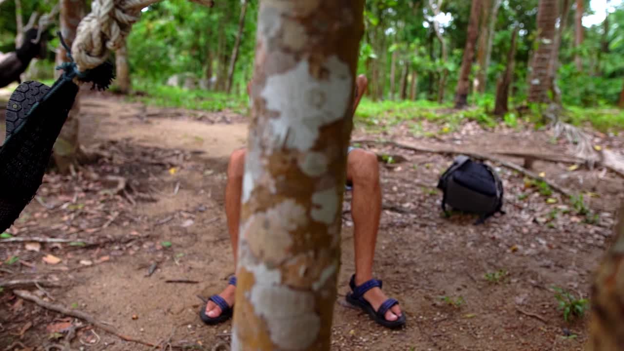 一名男子在森林中的吊床摇摆上休息的拍照
