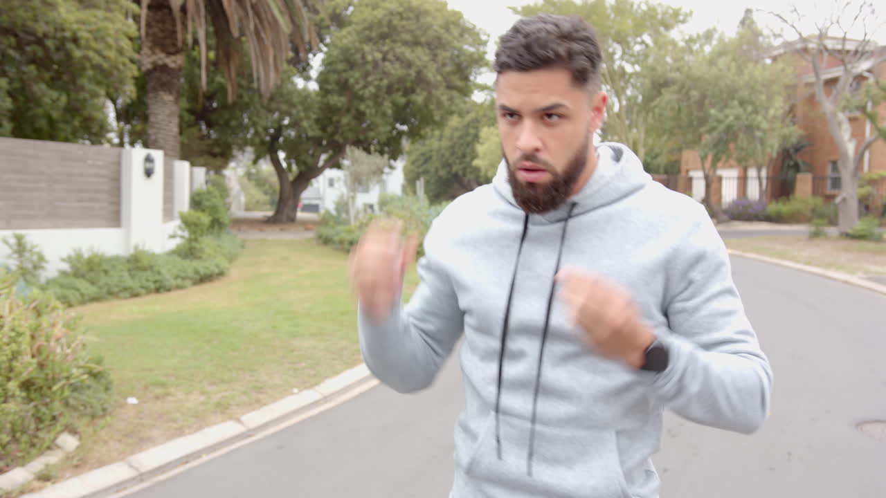 Boxing outdoors, man in hoodie practicing punches on suburban street