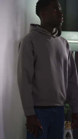 video vertical de un joven en casa hablando por teléfono móvil reaccionando y pareciendo molesto después de recibir malas noticias 1