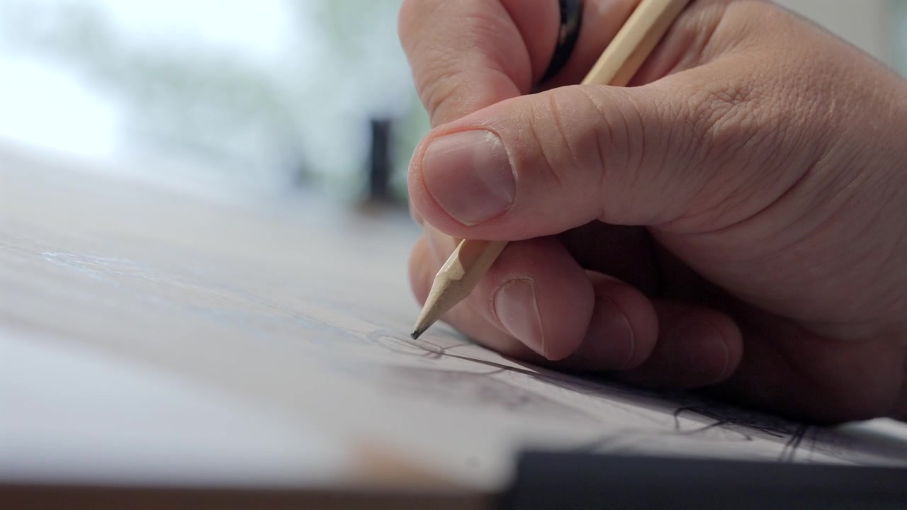 Immerse yourself in the world of design with this captivating slow-motion close-up. An architect's skilled hand meticulously renders intricate building plans on paper using a pencil.