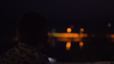 child looking at night sea from the house balcony