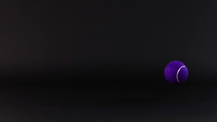 Tennis ball bouncing against a dark background