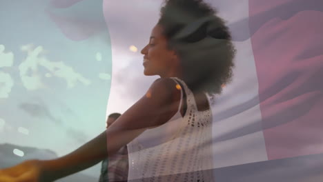 Animation-of-flag-of-italy-over-happy-diverse-couple-dancing-with-sparklers-on-beach-at-dusk