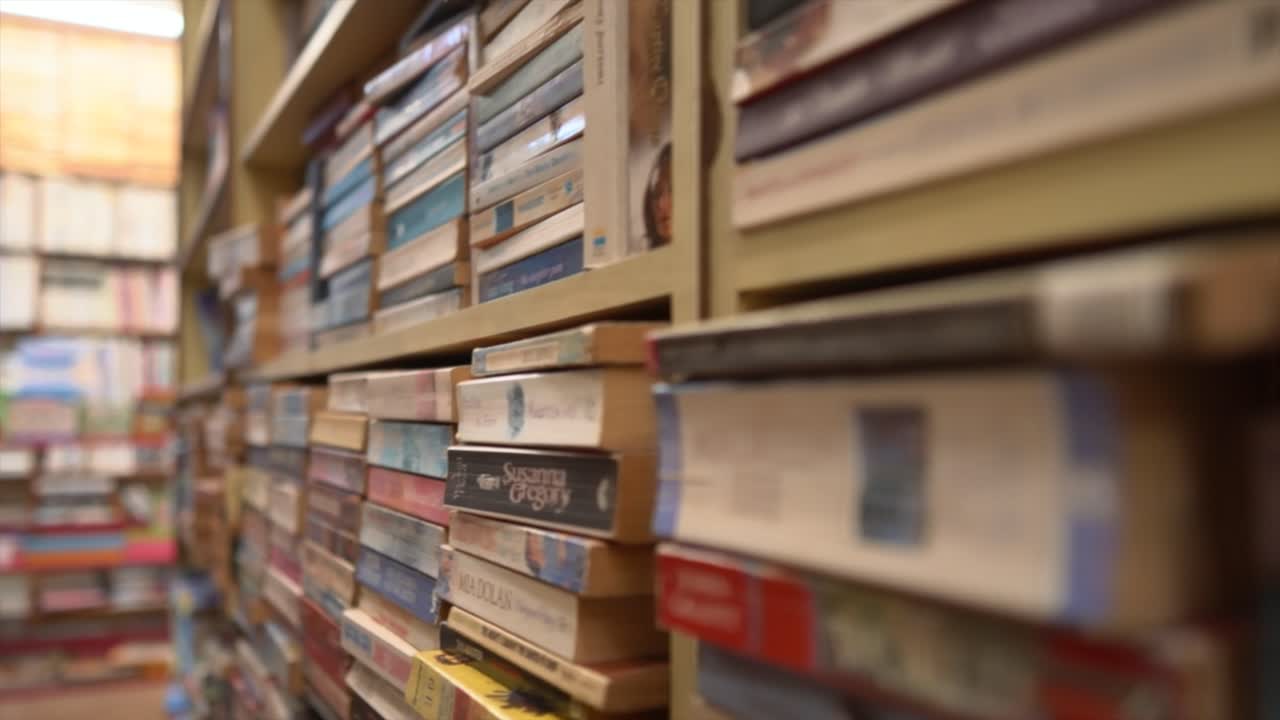 Tracking shot of variety of book stacks in a library, close-up