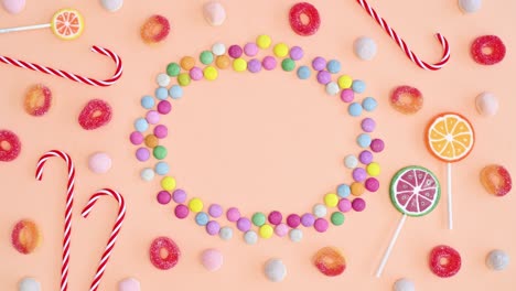 candies and lollipops creative arrangement frame copy space on bright pastel orange background. stop motion flat lay