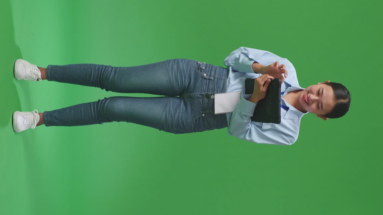 cuerpo lleno de mujer de negocios asiática usando tableta en el fondo de la pantalla verde en el estudio